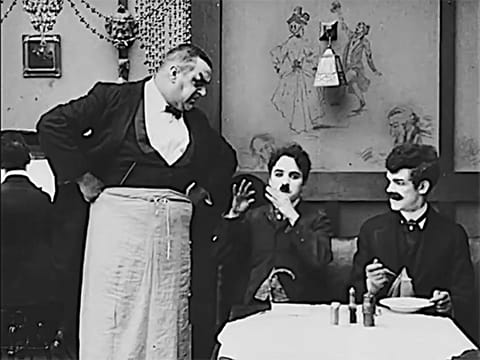 Charlie Chaplin pantomiming a flute