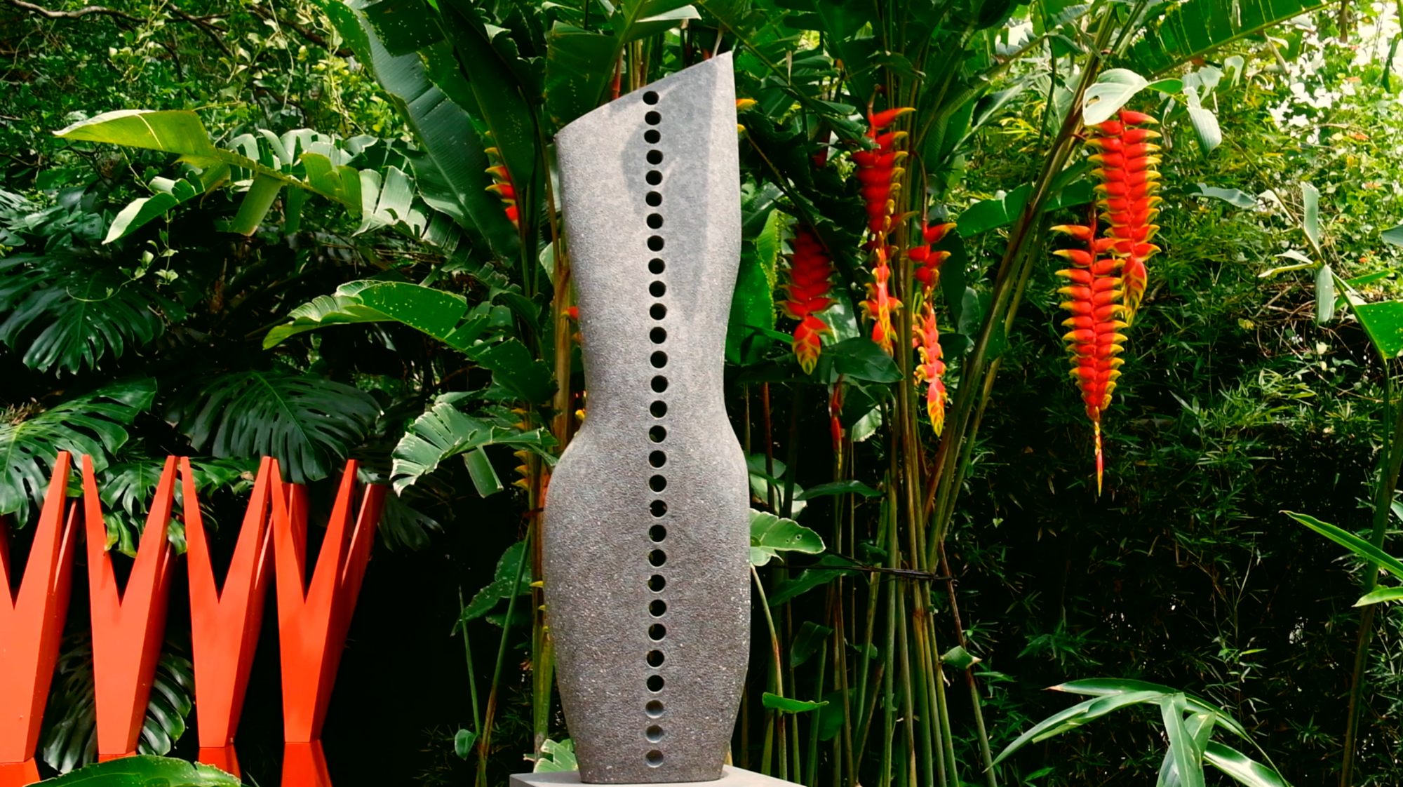 Un torso abstracto del cuerpo femenino hecho por el escultor José Sancho Benito, junto a unas heliconias en su jardín escultórico.