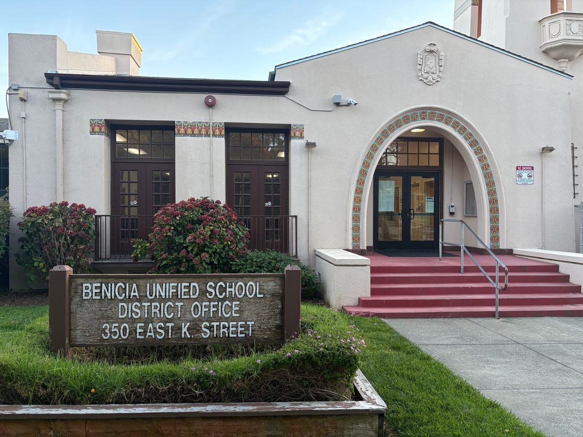 An older white building with a wooden sign reading "Benicia Unified School District Office 350 East K. Street" 
