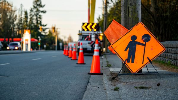 Orange cones and a caution, workers ahead sign, on a street as crews repair road