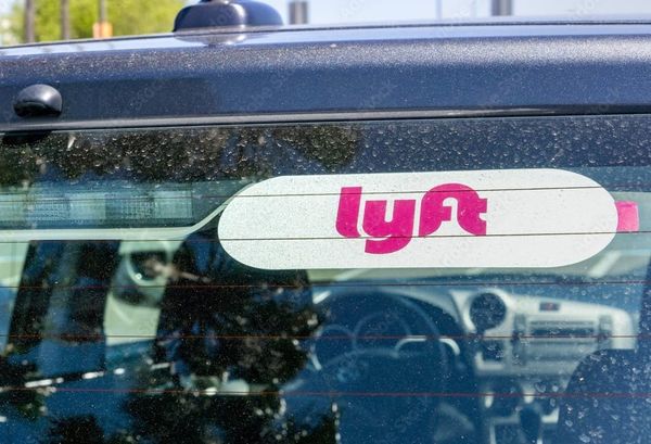 A photo showing the back windshield of a car with a pink and white Lyft logo. 
