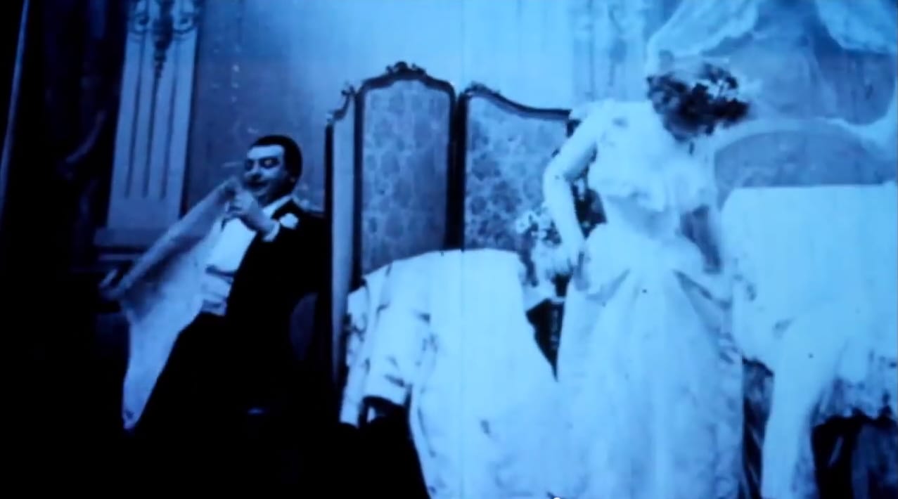A screenshot from the literal blue movie Le Coucher de la Mariée, which is believed to be the first striptease ever captured on camera