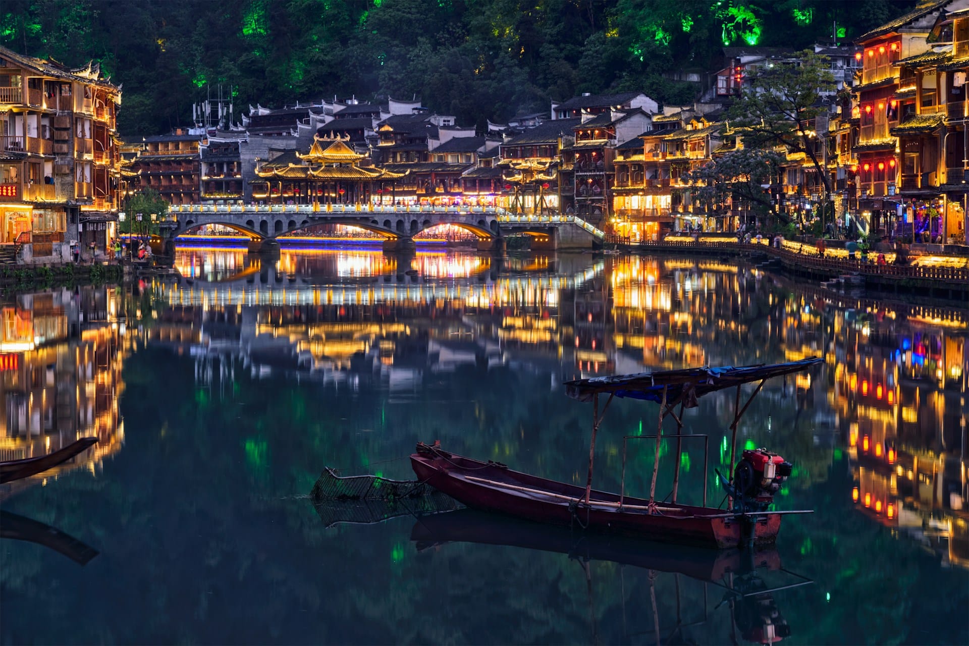 The breathtaking ancient town of Fenghuan in China's Hunan province, illuminated at night and reflected in the waters of the Tuojiang River (Image: Unsplash)