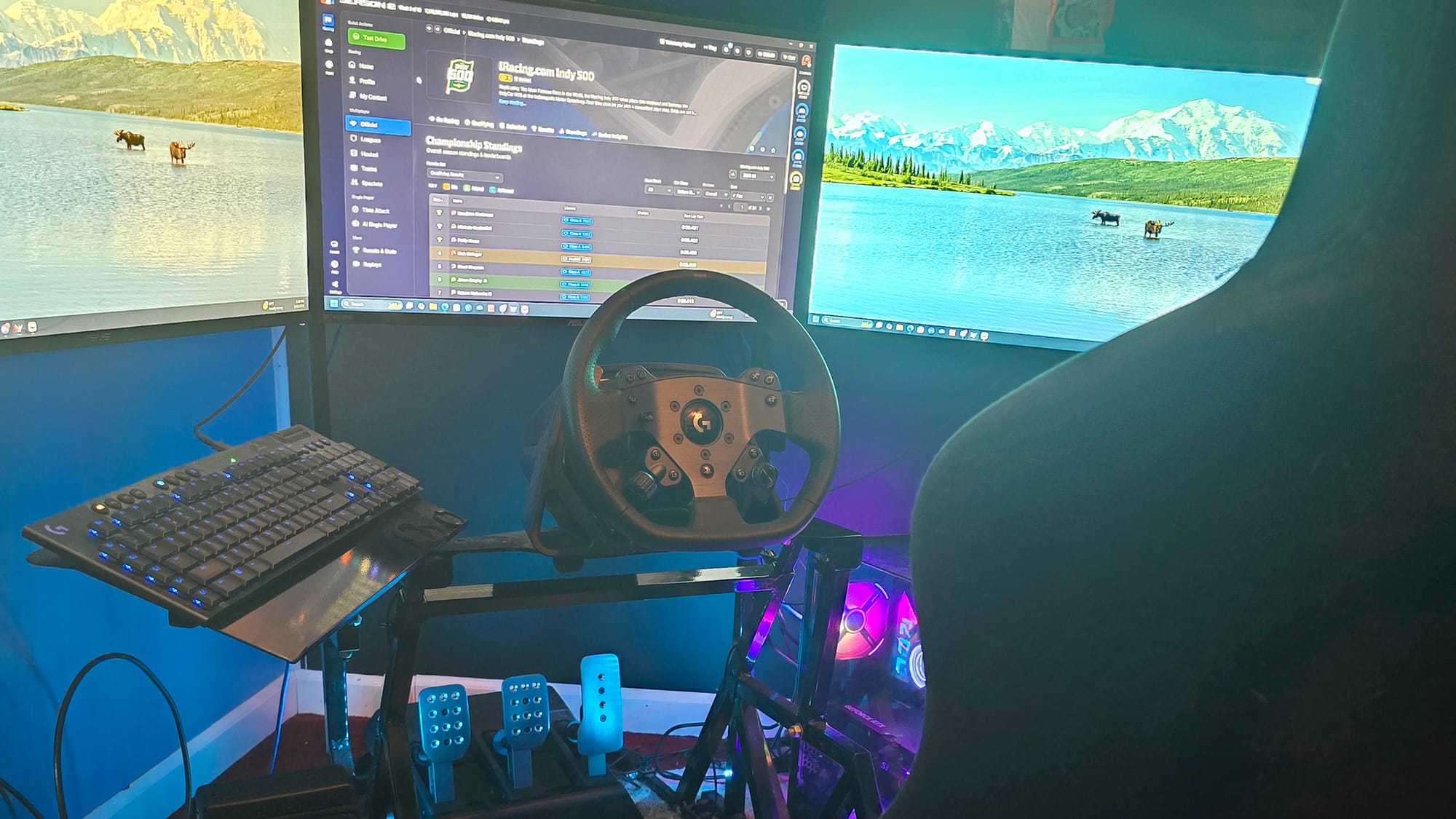 A professional iRacer simulation rig features three computers, a steering wheel and pedals.