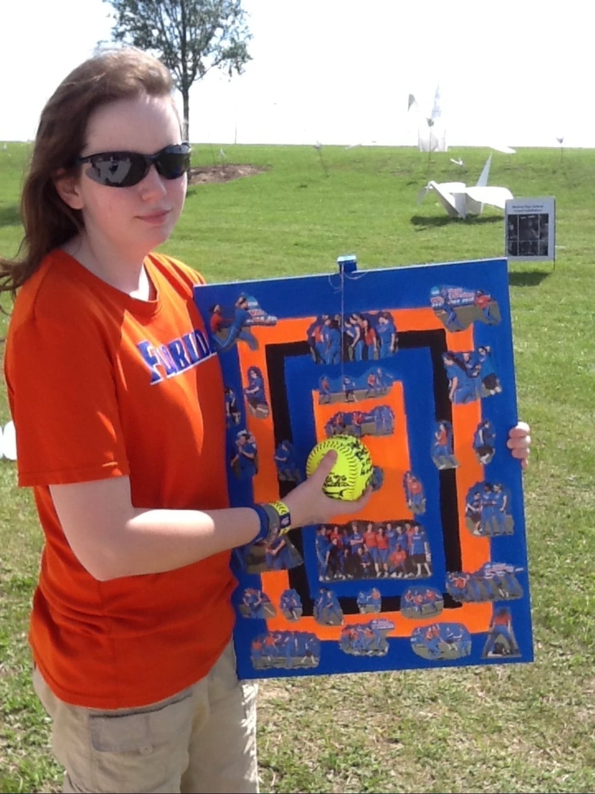 Heather Braswell stands with a board of photos Florida's players made for her, along with a signed softball. 