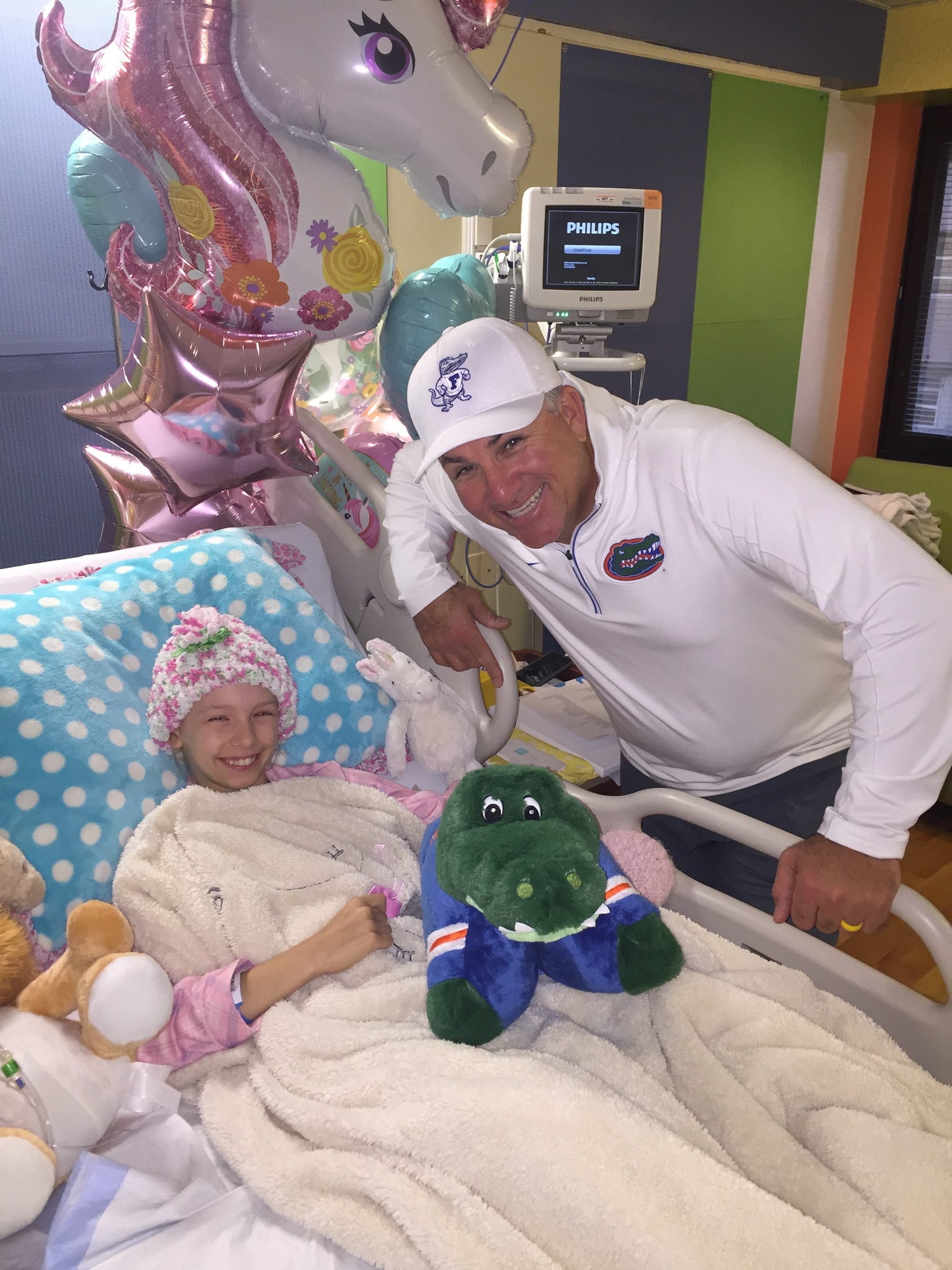 Hartley Georges lays in a hospital bed, posing with Florida coach Tim Walton, as she battles cancer.