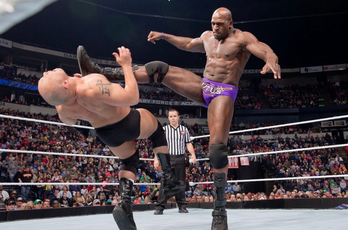 Titus O'Neil drop-kicks a WWE opponent during a match.