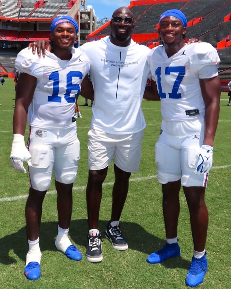 TJ (left) and Titus Bullard standing with their dad Thaddeus on the field of Ben Hill Griffin Stadium.