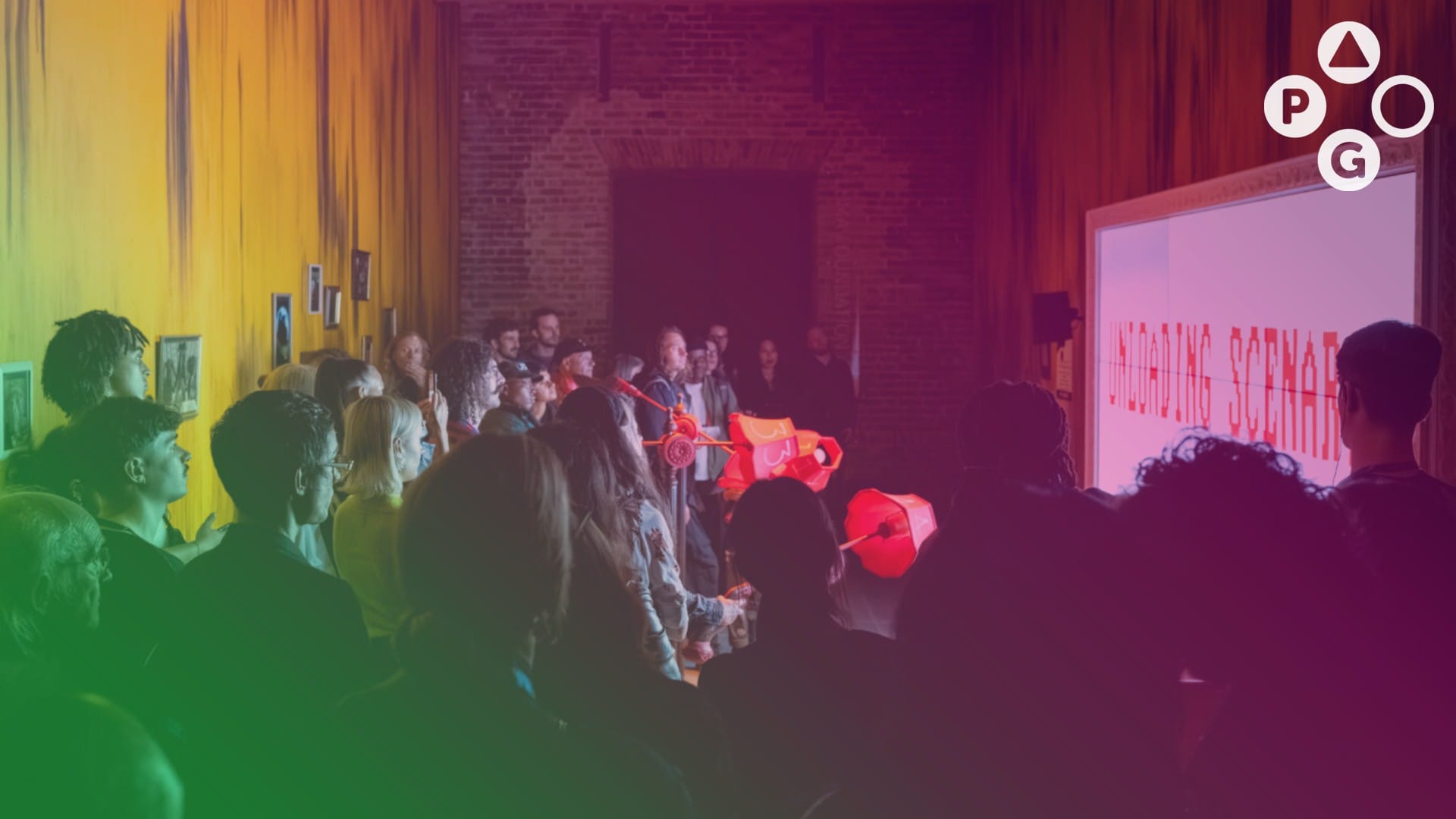 A group of people standing in a room with a huge projector on the wall. Text on the projector screen reads, "UNLOADING SCENARIO"