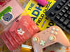 Several items on a desk: a keyboard, a pink video game controller, a pink pill organizer, a book titled The ADHD Field Guide for Adults