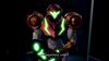 Samus wearing a power suit that's orange, gold, and white, facing the viewer. Dialogue text on the screen reads, "Any objections, Lady?"
