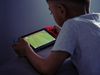 An over the shoulder shot shows a child holding a Switch and playing a soccer video game.