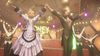 Cloud Strife, wearing a ruffled silk dress, stands on stage next to cabaret performer Andrea. They both have their hands raised in the air.