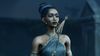 Hazel wears a black halter top donned with silver details, purple eyeshadow, and a full head of braids pulled into a bun at the crown of her head.