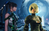 Two women standing next to each other. Eve (left) has long black hair and is wearing a white and green bodysuit; 2B (right) has platinum white hair and is wearing a gothic lolita dress.