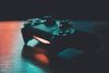 A close-up of a PlayStation controller sitting on a wooden surface in a dark room