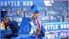 Eternity, the host of Street Fighter 6's Battle Hub, says into a microphone: "Are you a fighter looking for your next challenge?" They have blue hair and a blue and pink blazer