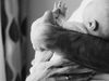 A close-up of a father's arms holding a baby, playing with the baby's hand.