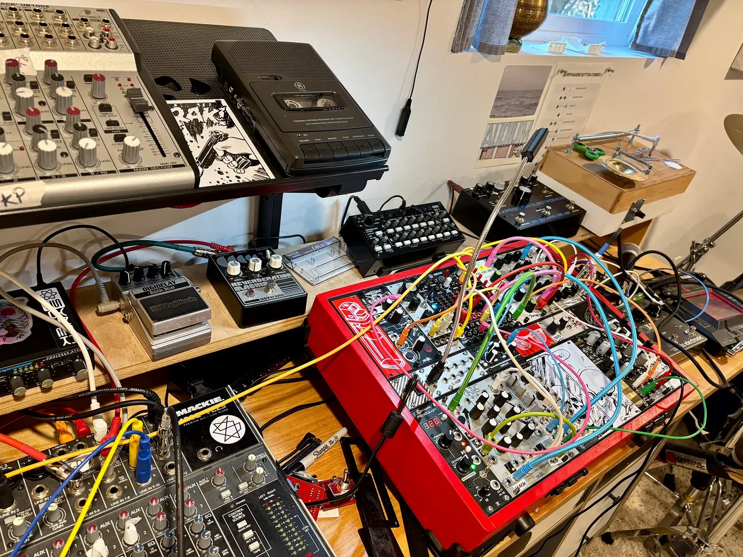 Music studio table featuring a mixer, effects pedals and a modular synthesizer case