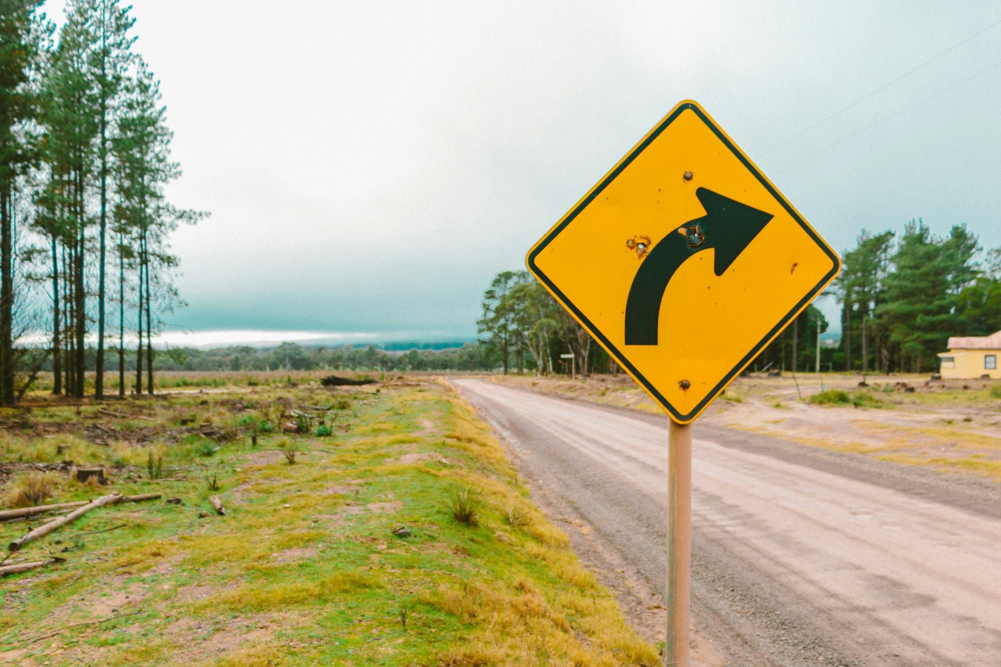 A dirt road on the background is complemented by a yellow traffic sign with an arrow pointing right.