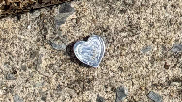 small metal heart resting on pavement