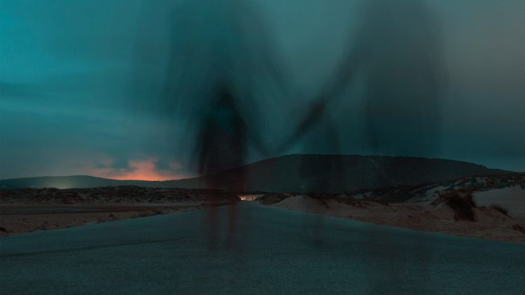 two ghostly figures walking away down a bleak road seemingly holding hands