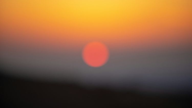 blurry shot of a sunrise or sunset, the sun an orange ball in the distance