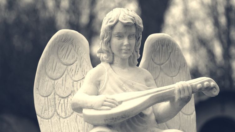 angel statue with musical instrument, possibly in an old cemetery