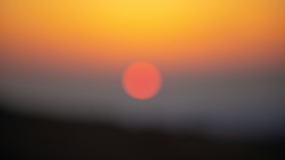 blurry shot of a sunrise or sunset, the sun an orange ball in the distance