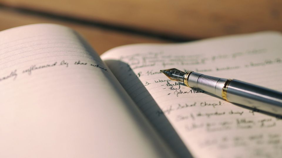 fountain pen lying on an open notebook with pages full of writing