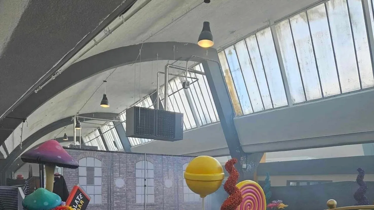 The ceiling of the warehouse is exposed, with its industrial fittings and fixtures, and its dirty skylights revealed.