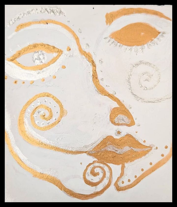 a stylised face made up of swirls of silver and mostly gold. one eye closed, one opened.