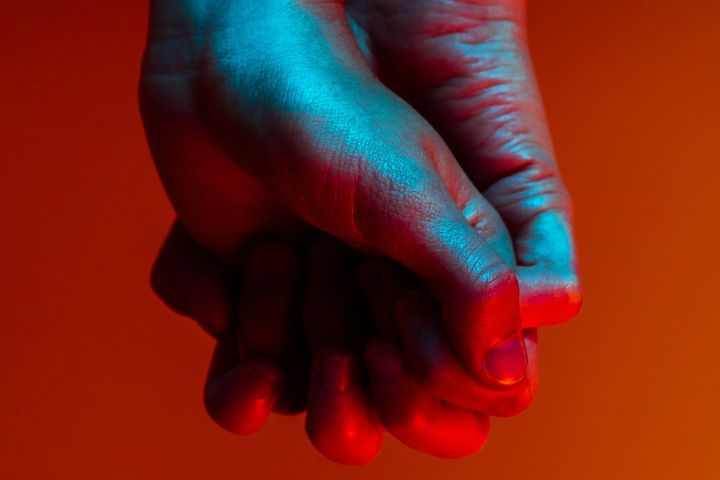 Two hands holding each other, one from the front one from the back