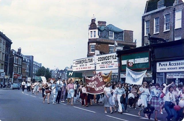 a colour photo of a march of mostly women in London supporting the minor;s with banners and a small police escort.