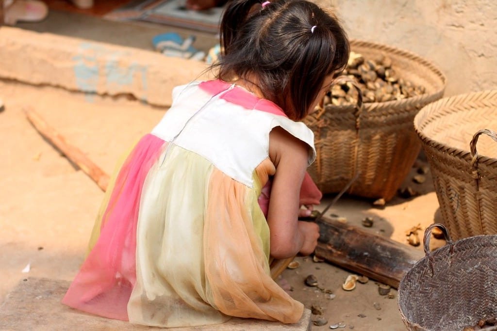 Young tribal girl holding a machete in a village along the Mekong River