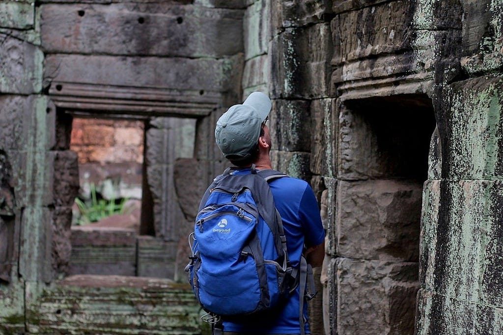 Travelers exploring the ancient Angkor temple ruins surrounded by jungle in Cambodia