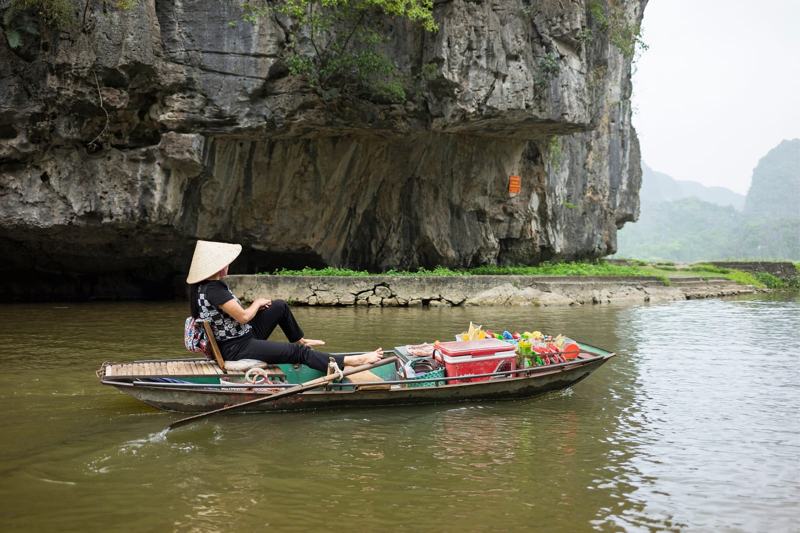 Vietnamese woman rowing a boat with her feet on the Ngo Dong River in Tam Coc
