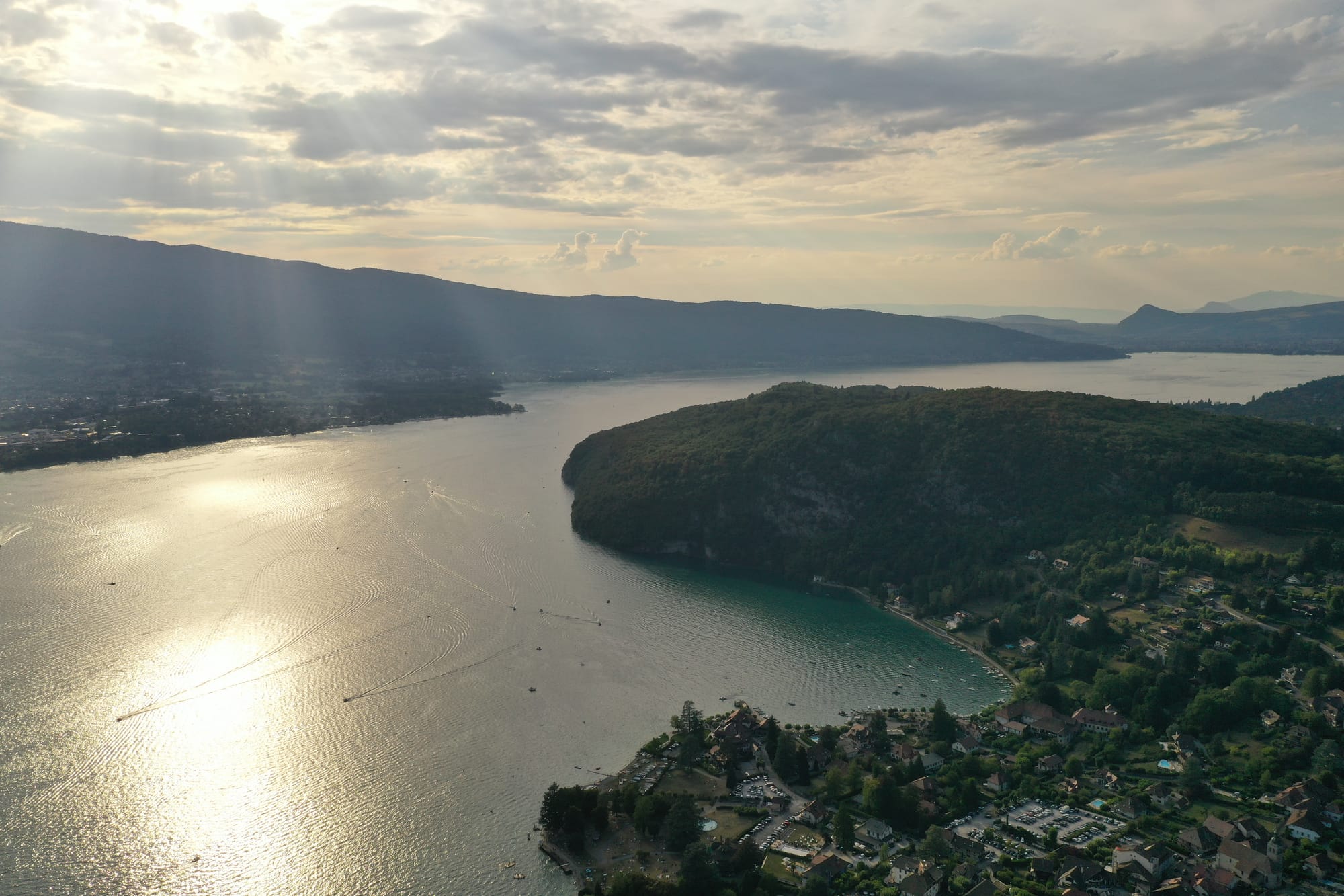 Aerial view of Lac d'Annecy at golden hour showing golden reflections on turquoise water and the wooded Duingt peninsula, captured with a DJI Mavic Pro 2 — Lac d'Annecy, France