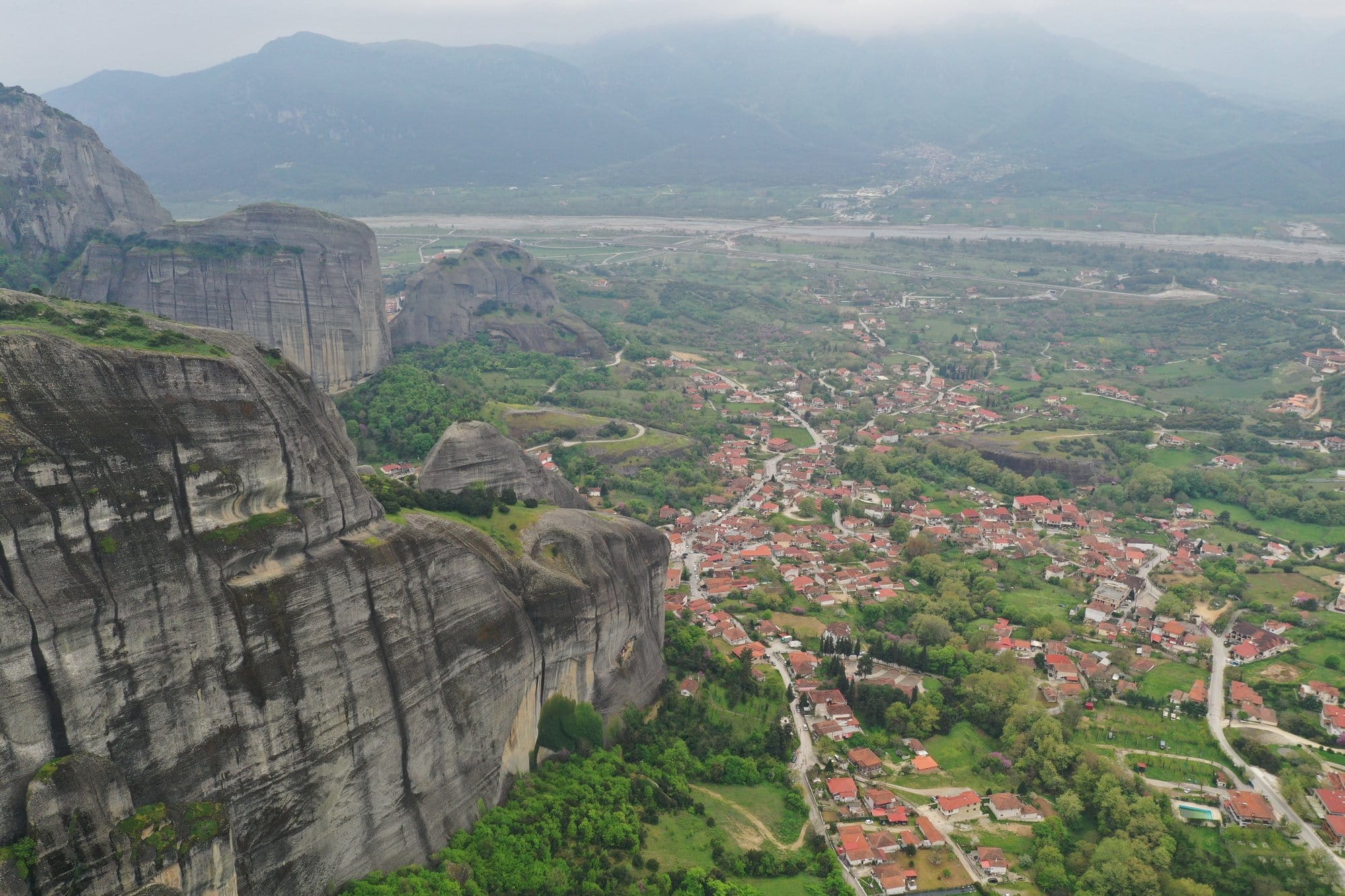 Aerial of Kastraki village wrapped around the Meteora rocks at golden hour — Greece