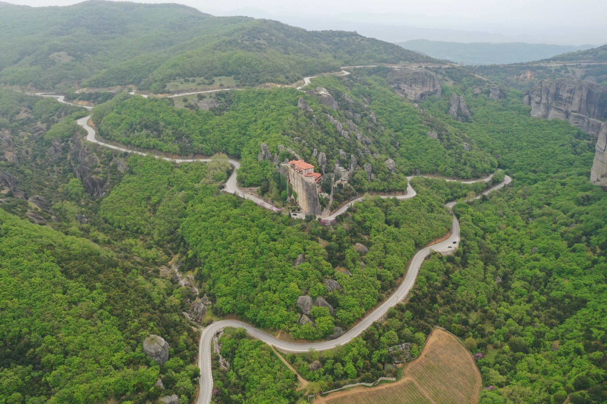 Vue aérienne d'un monastère de Meteora entouré de forêts et de routes sinueuses — Grèce