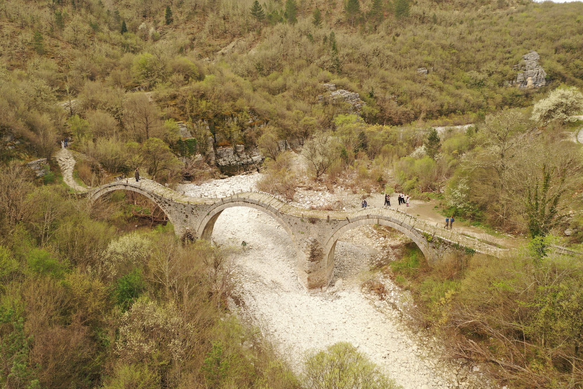 Triple-arched stone bridge spanning a dry riverbed in Zagori — Greece