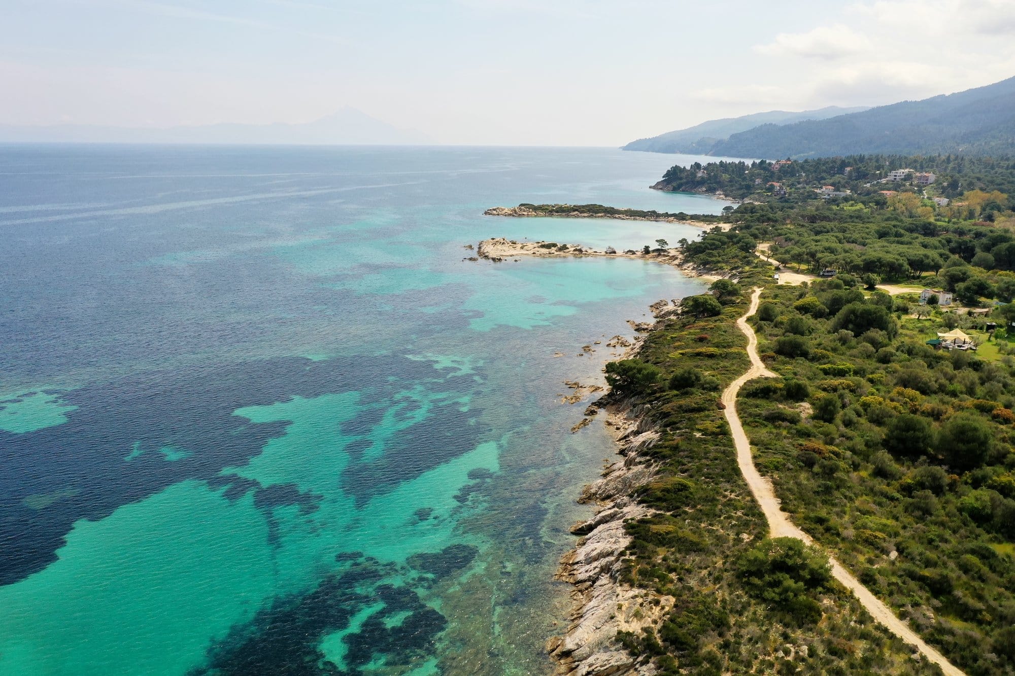 Vue aérienne d'un littoral boisé de pins à Sithonia avec eau turquoise et sentier côtier — Grèce