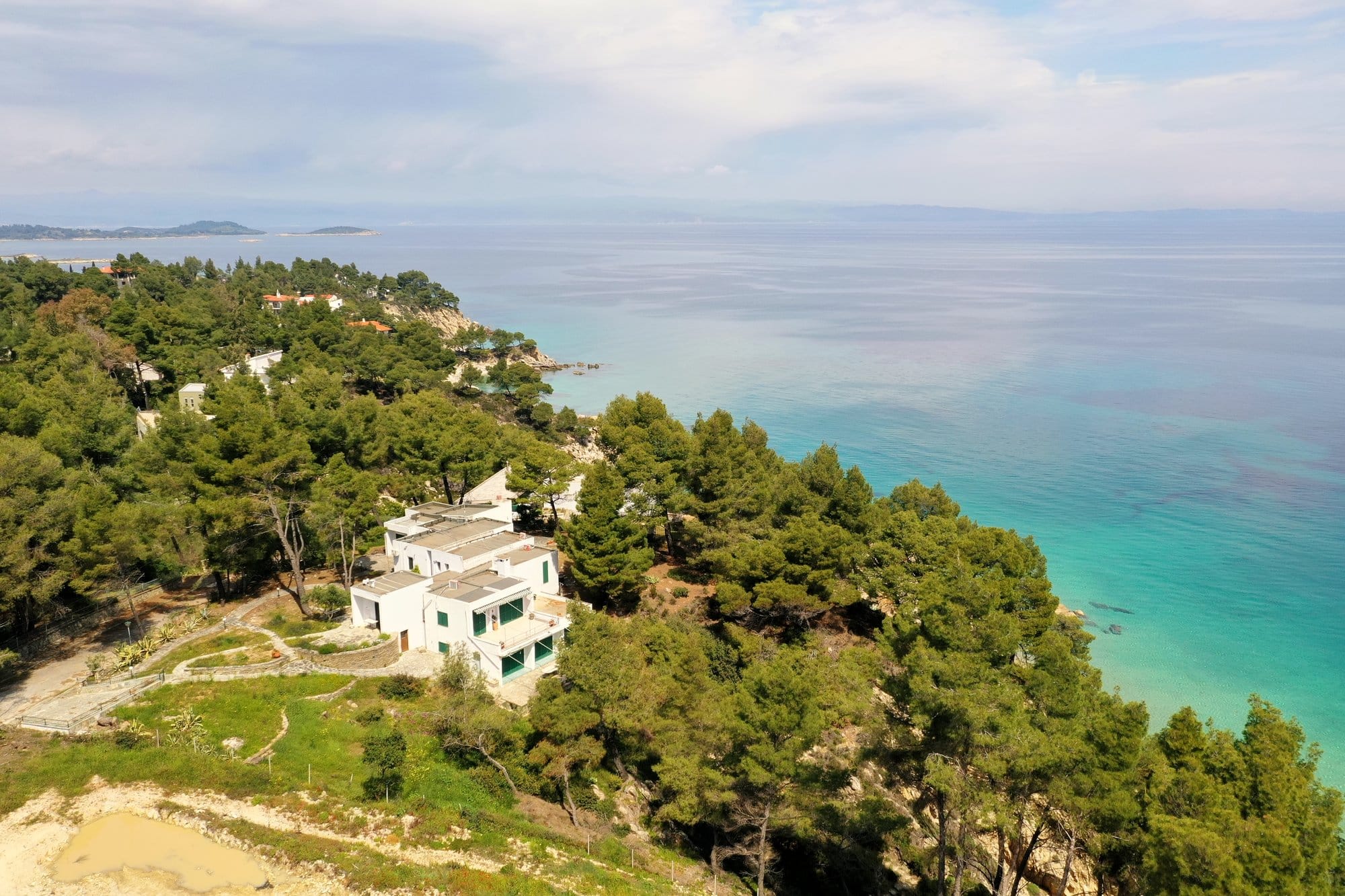 Vue aérienne d'une villa blanche moderne sur un cap de Sithonia couvert de pins — Grèce