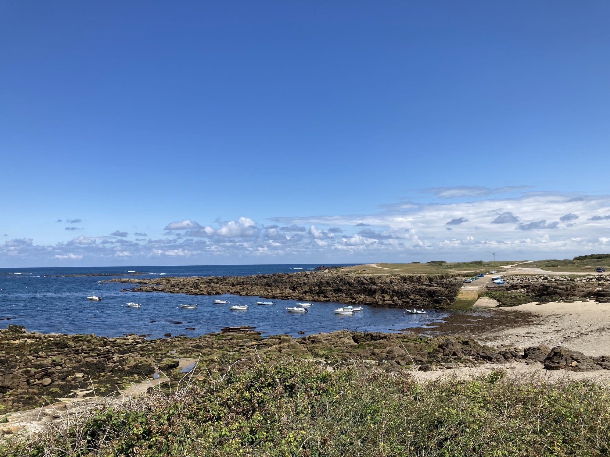 Small fishing boats moored in the turquoise waters of Port de la Meule, a rocky natural harbour on Île d'Yeu's south coast — Île d'Yeu, France