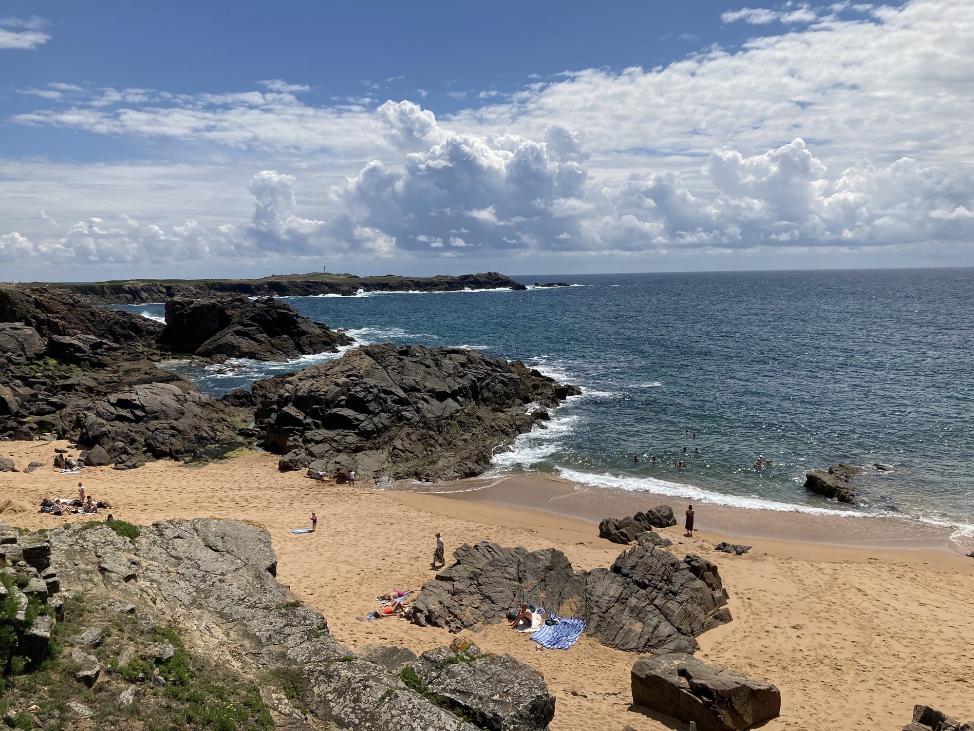 Golden sand beach of Plage des Vieilles framed by dark granite rocks, waves breaking gently on the shore — Île d'Yeu, France