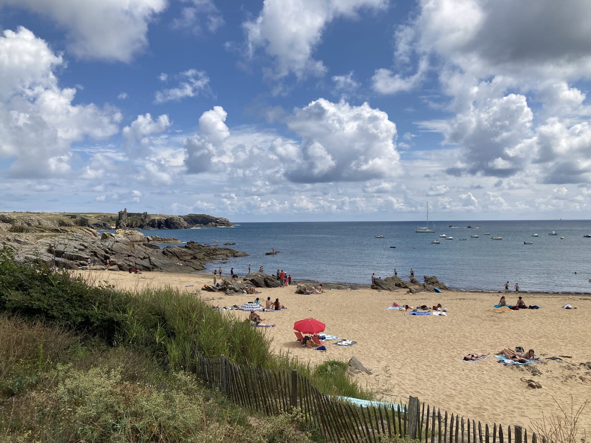 Plage des Sabias panorama with golden sand, sunbathers and the distant silhouette of the Vieux-Château on the horizon — Île d'Yeu, France