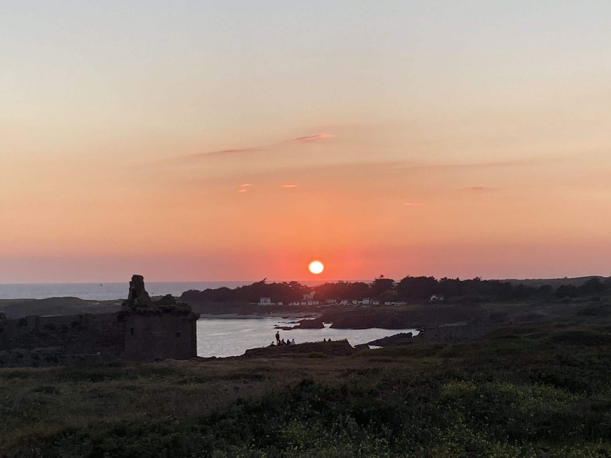Sunset over the Vieux-Château silhouette, the sun dropping into the Atlantic behind the medieval ruins — Île d'Yeu, France