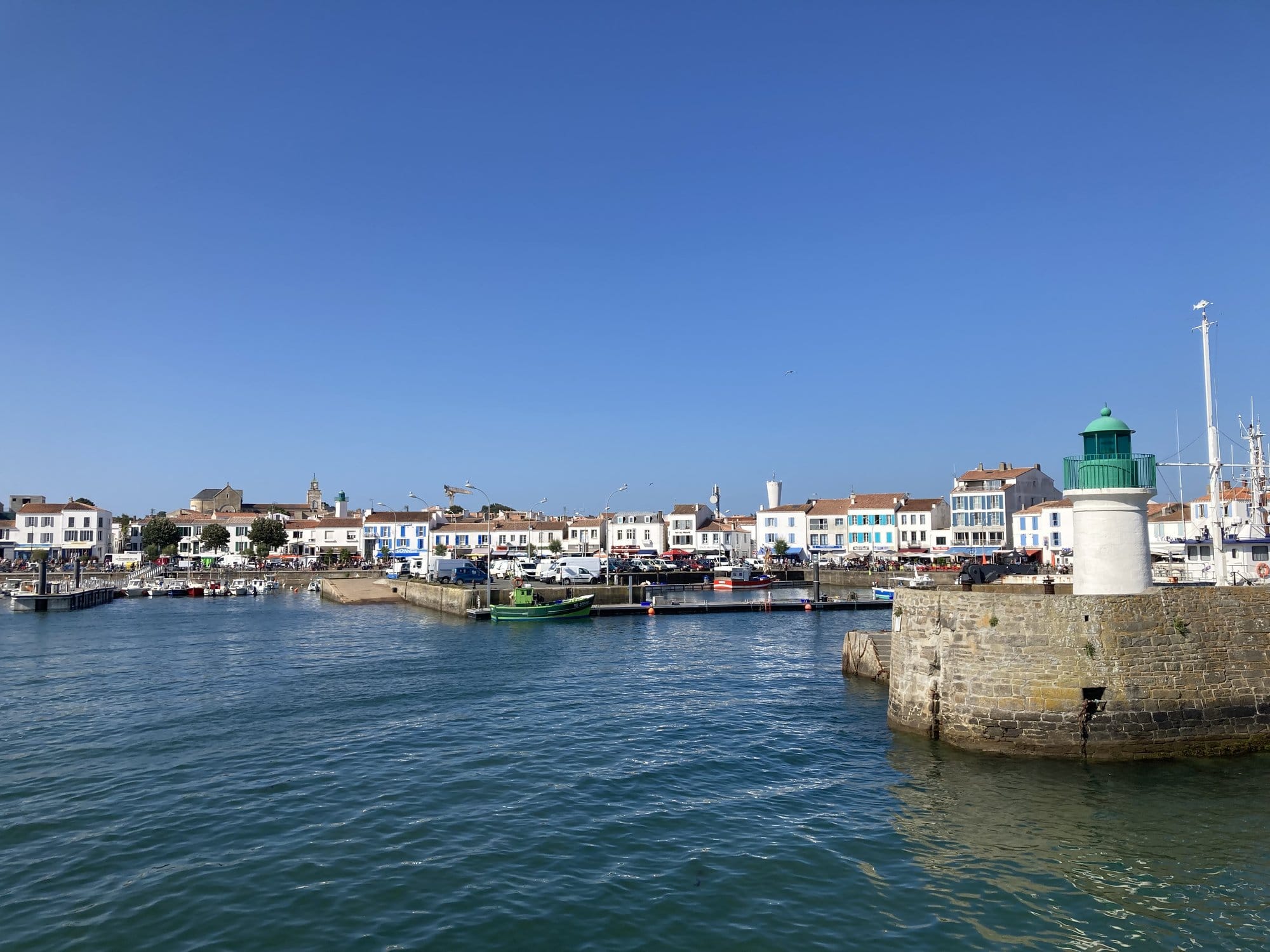Panoramic view of Port-Joinville harbour from the ferry, colourful waterfront buildings and the green lighthouse on the jetty — Île d'Yeu, France