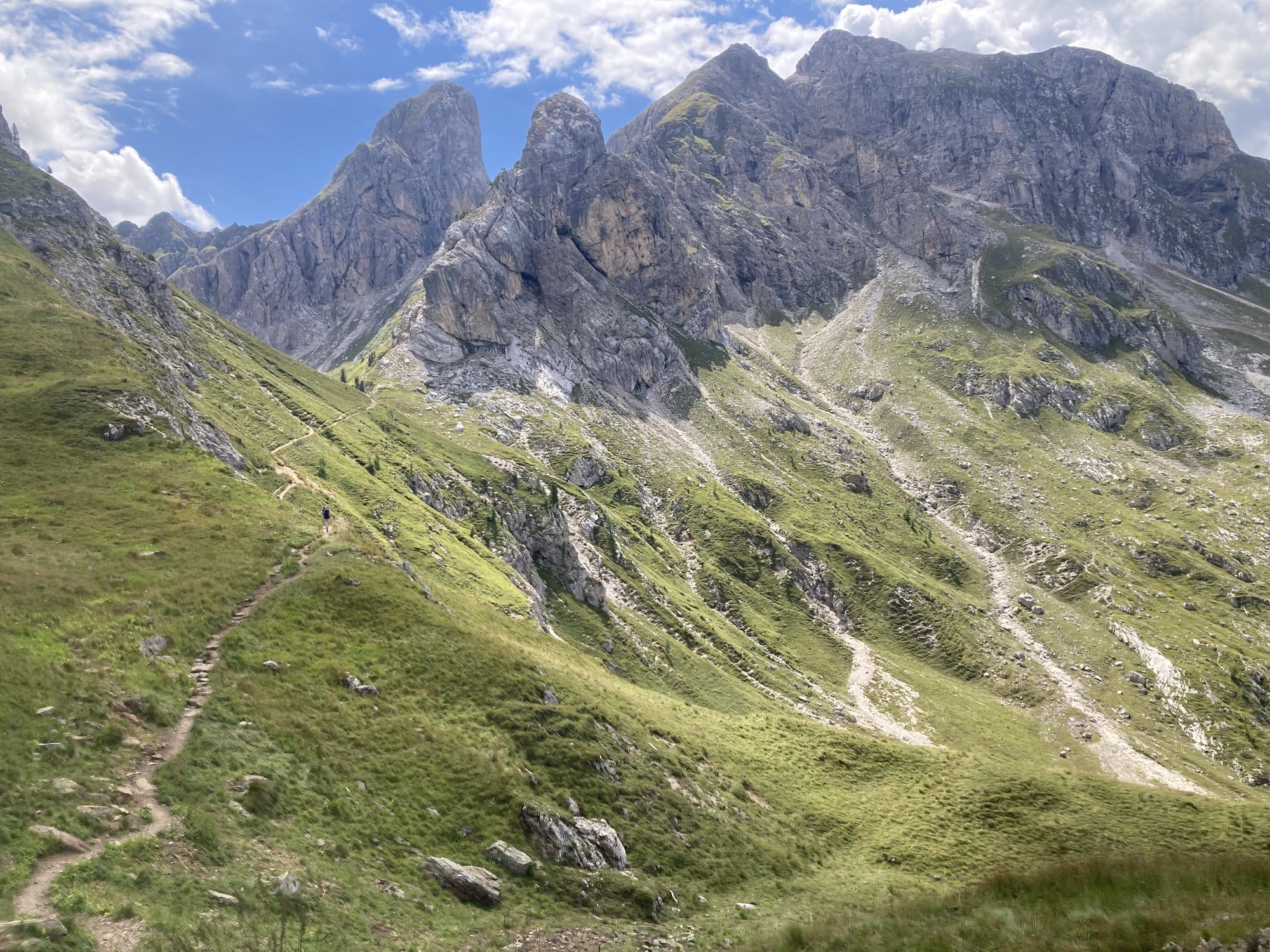 Hiking trail ascending through alpine meadows toward Passo Giau with rock walls — Dolomites, Italy
