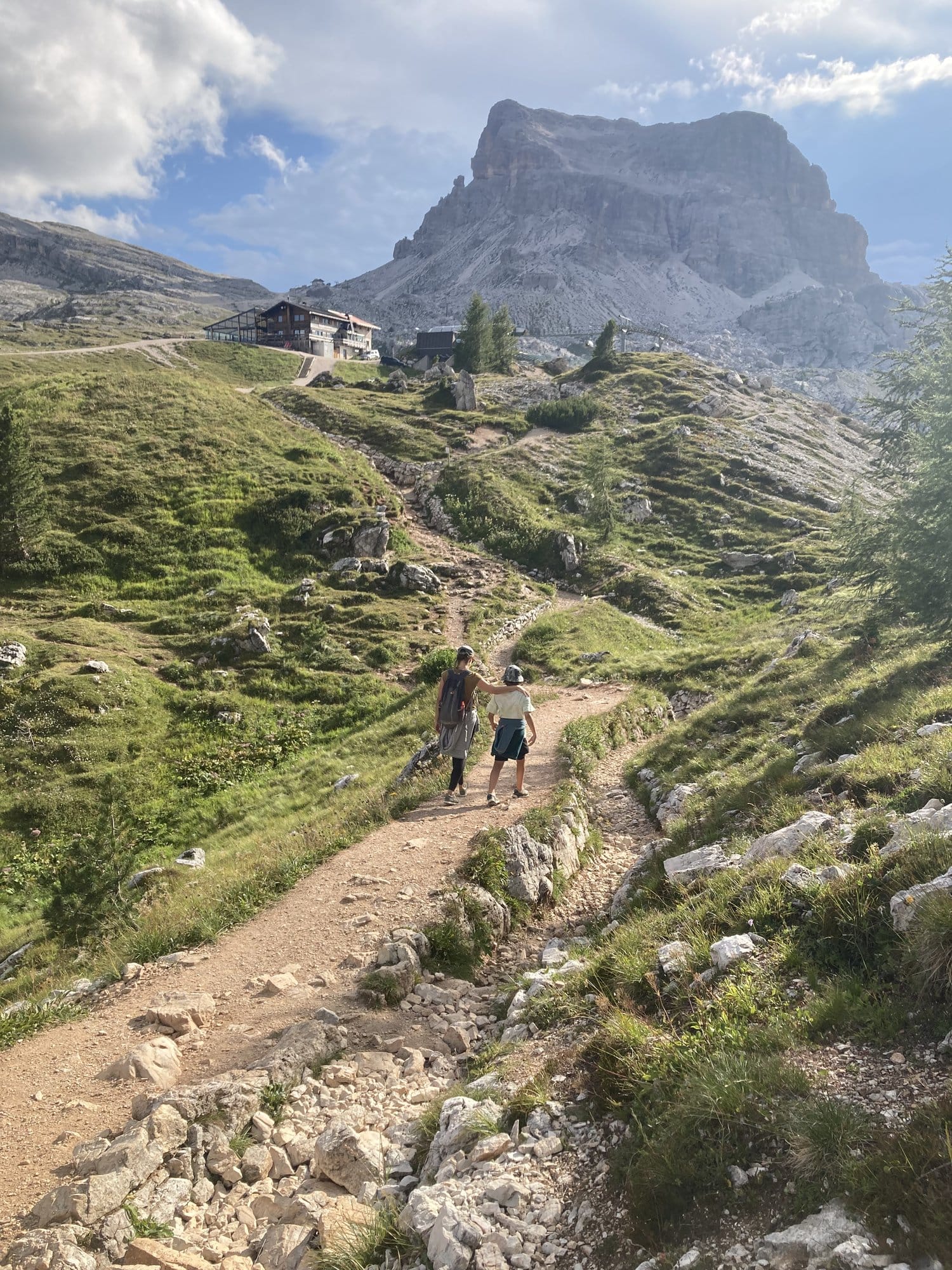 Two hikers on the trail toward Rifugio Averau with Tofana di Rozes in the background — Dolomites, Italy